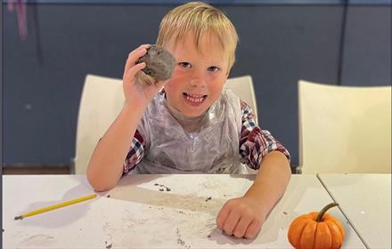 Child holding a clay pumpkin candle holder