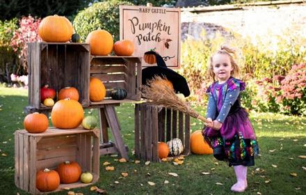 Image of a child dress as a witch next to a display of pumpkins at Raby Castle.