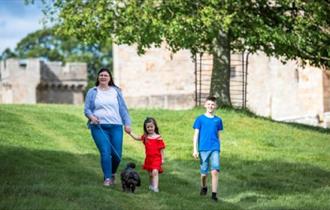 Family enjoy a walk in the Deer Park at Raby Castle with their dog.