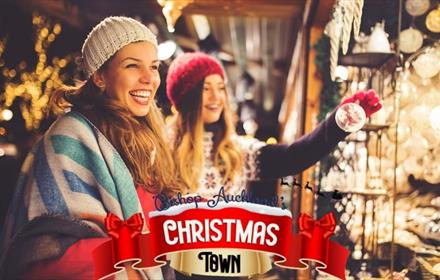 Image of two people smiling, and looking at Christmas decorations on sale in one of stalls at Bishop Auckland's Christmas Town.