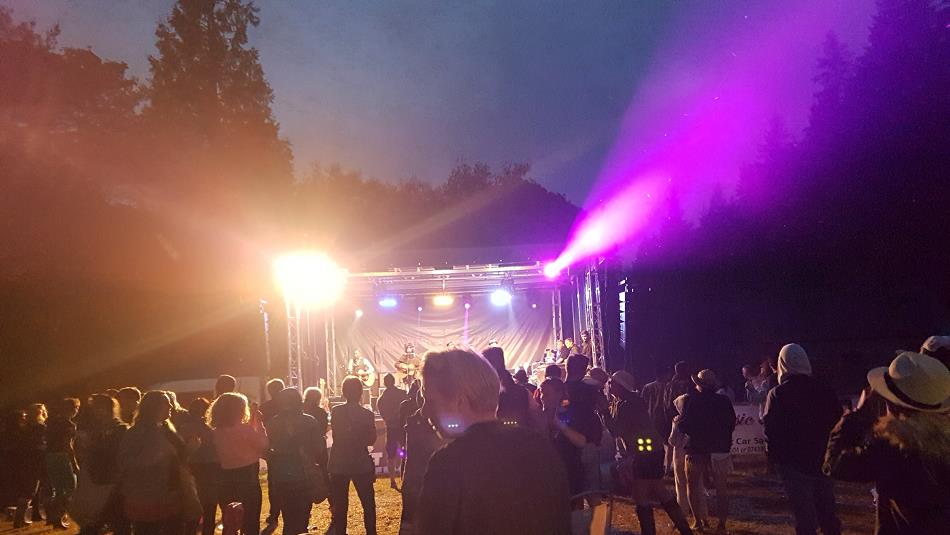 Scoop festival at night with band performing on lit stage and crowds of people watching