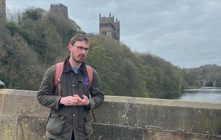 A tour being delivered on Framwellgate Bridge, with the River Wear and Durham Cathedral in the background.