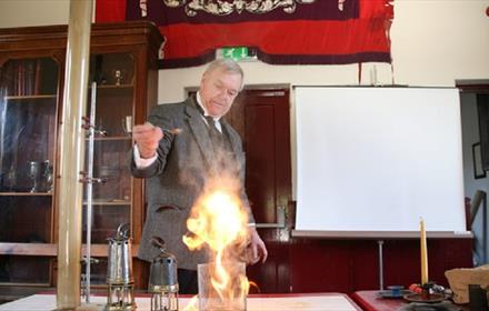 Man dressed in period clothing demonstrating an experiment with fire