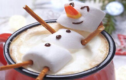 Image of marshmallows arranged to look like a snowman in a hot chocolate drink.