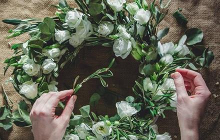 Hands on a spring wreath with white roses.