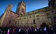 Durham Cathedral with people taking part in lantern parade walking towards entrance
