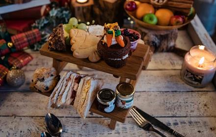 Image shows a selection of sweet and savoury treats, such a sandwiches, jams and fruits, for a Festive Afternoon Tea.
