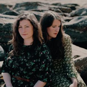 Two members of the act, 'The Unthanks' sitting on some rocks. 