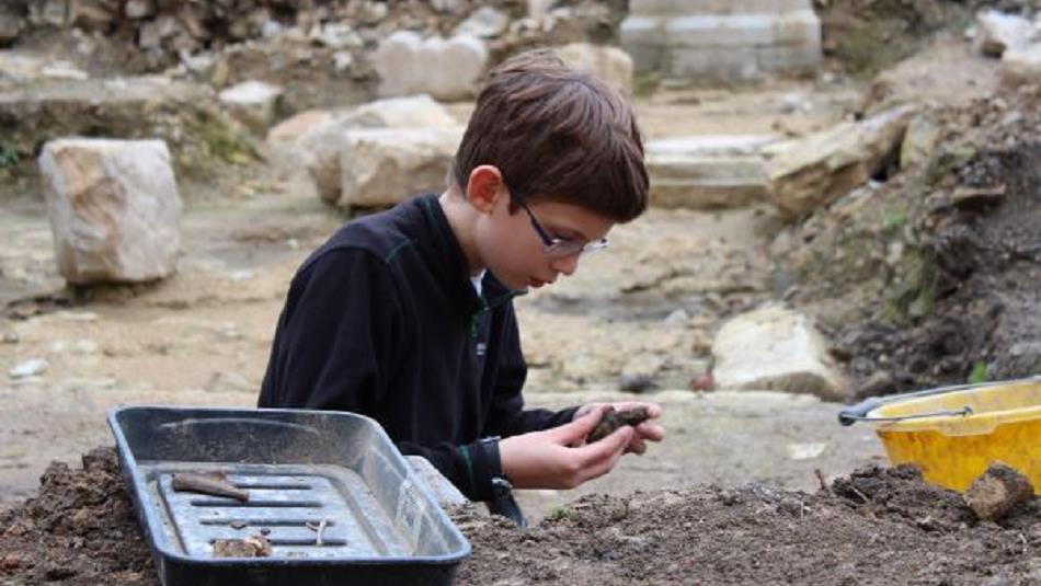 Image of a child examining objects found in an archaeological dig.