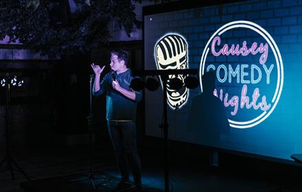 Image of a comedian performing on stage at South Causey Inn.