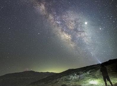 Image of someone stargazing outdoors in the countryside on a beautifully clear night.