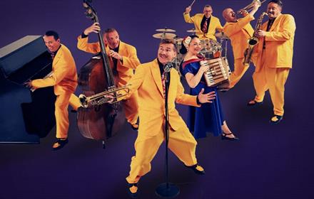 Image of 'The Jive Aces' performing in their iconic yellow suits.