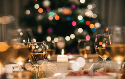Image of a table set for festive dining with fairy lights and wine glasses.