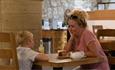 woman and child sat at table inside Durham Cathedral Restaurant.