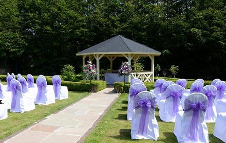 Image of a beautiful outdoor wedding space at Hall Garth Hotel. The gazebo and chairs are dressed in purple for a ceremony.