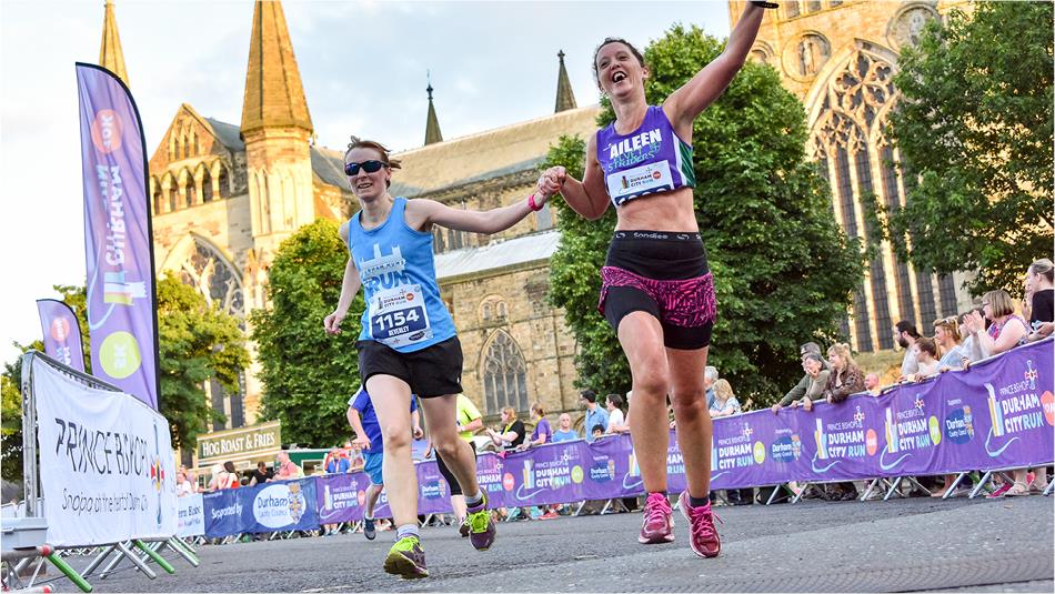 Female runners crossing the finish line of the Durham City Run