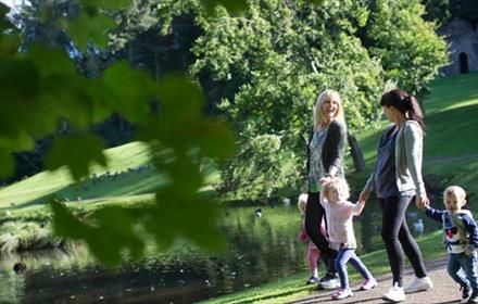 Two women and three children walking around the lake at Hardwick Park