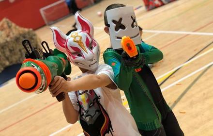Two children wearing masks and holding Nerf guns.