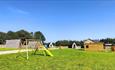 Children's play area with glamping pods in the background at Alma Meadow Glamping.