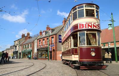 Burgundy and cream old-fashioned tram at Beamish Museum. 'Shop at Binns' written in red on tram