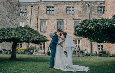 Image of a couple on their wedding day posing for photographs outside of Walworth Castle.
