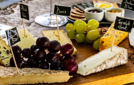 A cheeseboard showing produce by Teesdale Cheesemakers. Red and green grapes and selection of crackers and dips complement the cheese. 

Copyright: Te