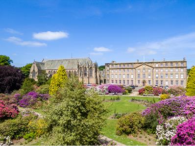 Ushaw and grounds on a bright, clear day, surrounded by purple shrubs.