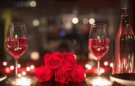Image of red roses, prosecco and soft fairy lights.