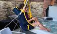 A person using a hoist to get into a hot tub