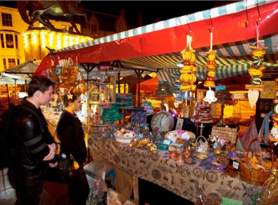 couple admiring products on an outdoor stall at Durham City Christmas Festival.