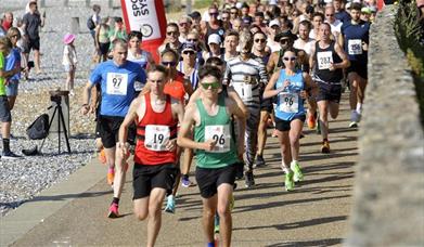 Group of runners in a race running on a path alongside a pebble beach