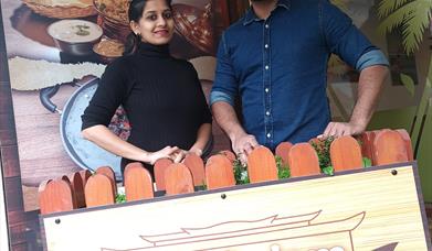 Malayalam Restaurant - picture of two people stood smiling in front of the business signage that reads 'Malayalam'