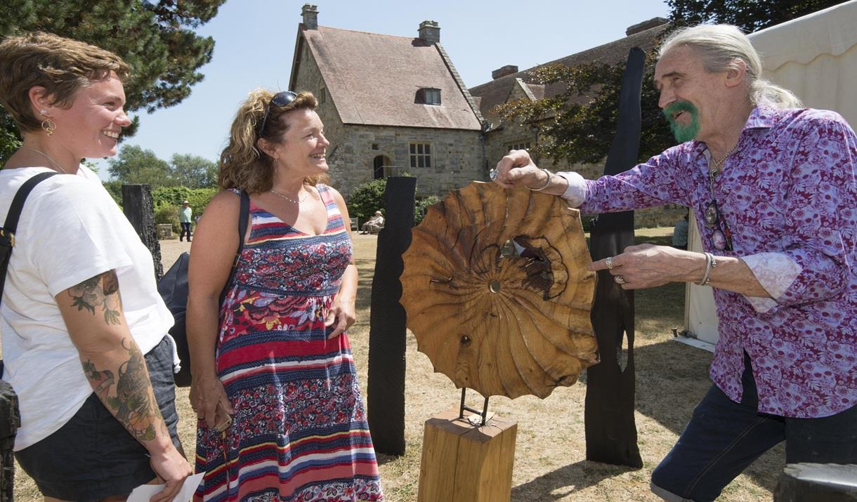 woodworker shows his craft to two smiling onlookers
