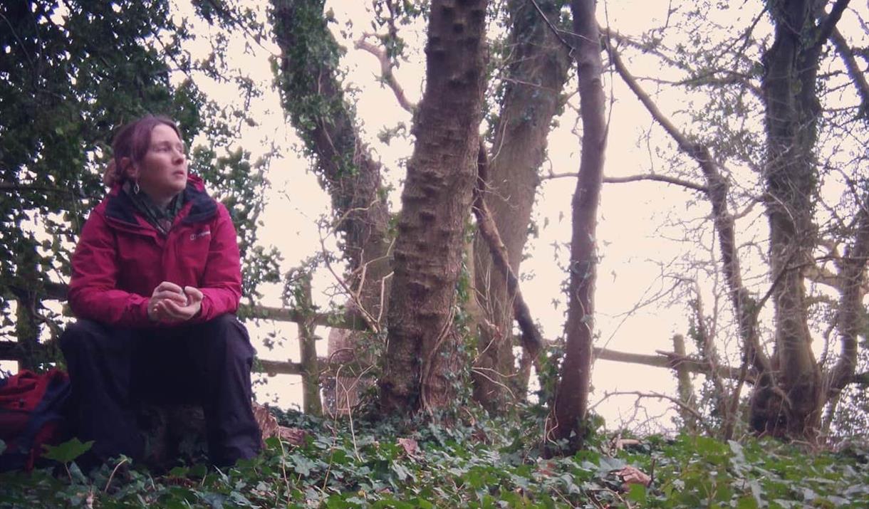 Dawn Nelson, storyteller, sitting in woodland