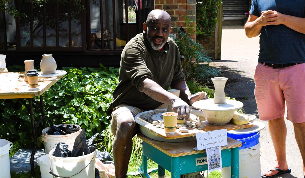 Man demonstrates making pottery using a wheel