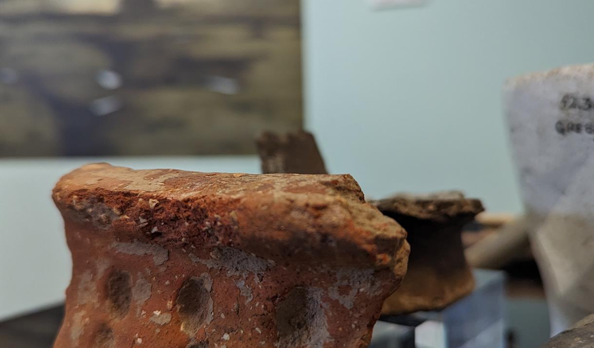 Piece of a rim from a prehistoric pot made from orange clay with circular decoration around edge