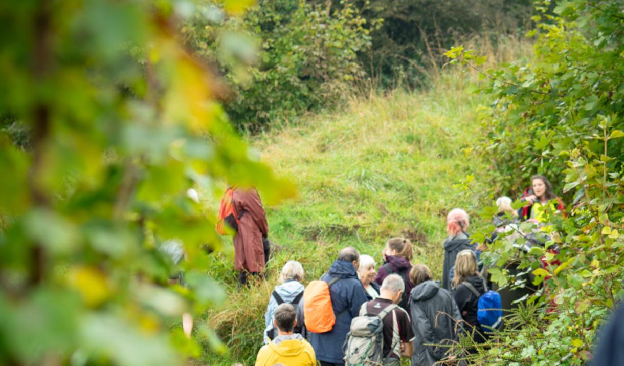 Group of people walking along path on Downland surrounded by greenery