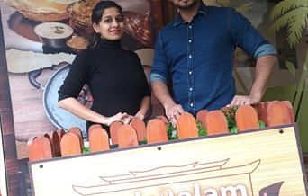 Malayalam Restaurant - picture of two people stood smiling in front of the business signage that reads 'Malayalam'