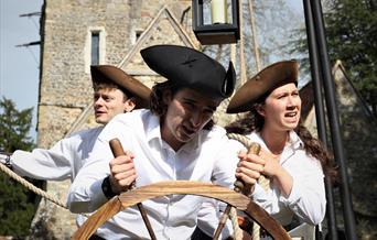 Two men and a woman aboard a boat in this play outside a church
