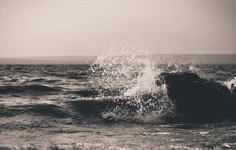 Spray from a wave in the middle of a grey sea