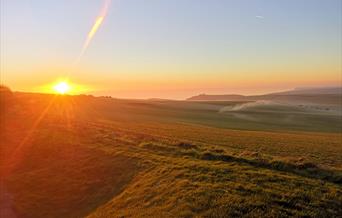 view from the Beachy Head Story towards Belle Tout with sun setting on left of image