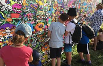 Children colouring in artwork on a wall