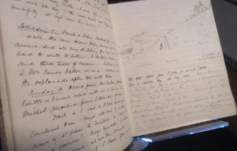 view of an open sketchbook full of writing and sketch of downland in eastbourne from 1870s