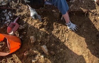 Archaeologist digging in flints and brown soil