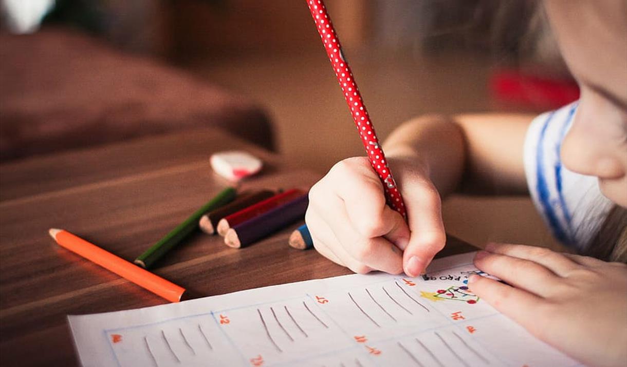 Child writing with red pencil