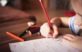 Child writing with red pencil