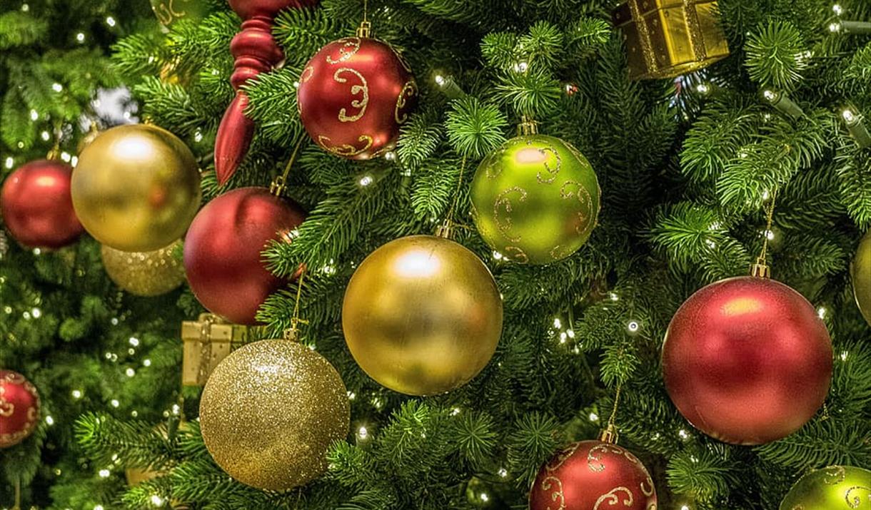 Close up of green christmas tree with red and gold baubles and small lights