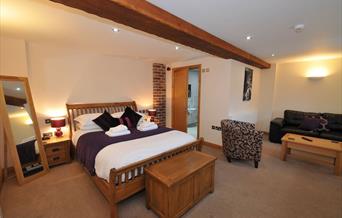 Aa spacious double bedroom with tub chair, coffee table and sofa at Ramblers Rest Luxury B&B in East Yorkshire.