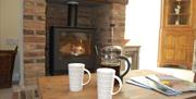 The log burner with 2 mugs and a full cafetiere on the coffee table at Rose Cottage in East Yorkshire.