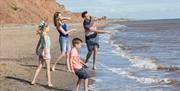 A family playing by on the beach by the sea near Withernsea Sands in East Yorkshire.